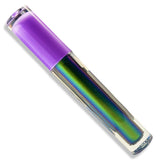 A clear cylindrical cosmetic tube containing an iridescent holographic lip gloss that shifts between green, blue, and purple, with a solid purple cap, shown on a white background.