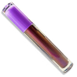 A clear cosmetic tube containing an iridescent red liquid with a metallic purple cap, shown diagonally on a white background.