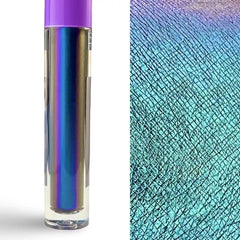 A clear cylindrical cosmetic tube with a purple cap stands on a white background beside a close-up swatch showing an iridescent holographic finish that shifts between blue, purple, and teal.