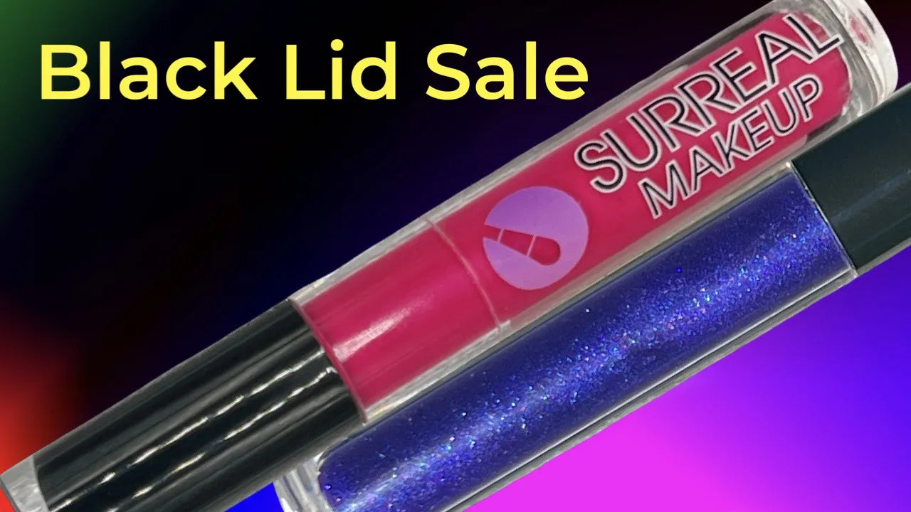 Two tubes of SURREAL MAKEUP liquid eye shadow shown diagonally on a colorful gradient background with yellow text reading 'Black Lid Sale'. One tube contains bright pink eye shadow, and the other contains sparkling blue-purple eye shadow with a black cap.