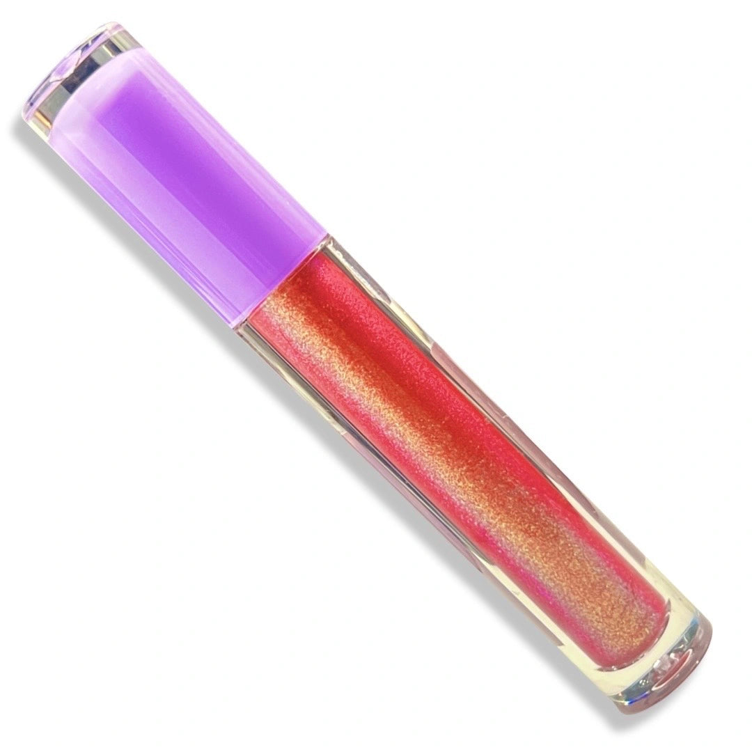 A tube of shimmering liquid lip gloss or lipstick with a translucent purple cap, showing a pinkish-red color with gold shimmer inside a clear tube, set against a plain white background.
